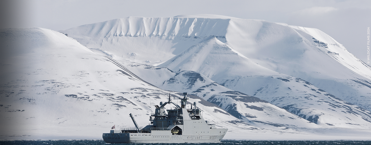 bateau de guerre devant un glacier de l'Arctique